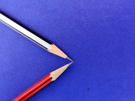 Copy space of red and black color pencil pointing each other on blue backgroundの写真素材