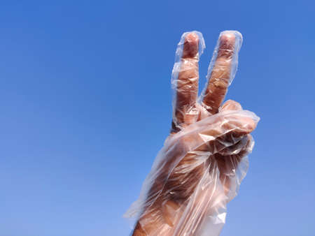 South Indian Male hand wearing disposable plastic gloves and showing victory sign or peace sign....