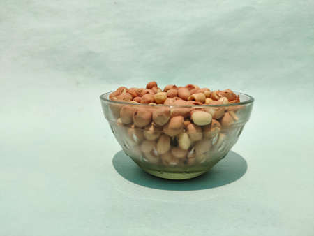 Side view of glass bowl full of ground nuts isolated on green background