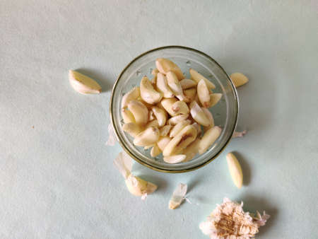 Top view of glass bowl full of peeled garlic pieces isolated on green backgroundの写真素材