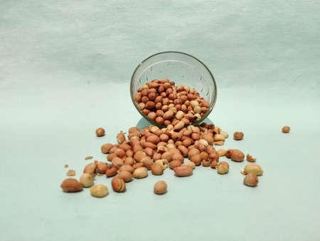 Ground nuts split from glass bowl isolated on green background