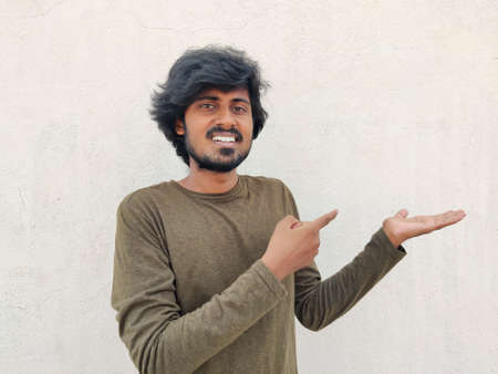 Super excited smiling tamil man pointing finger at copy space on his palm. White backgroundの写真素材