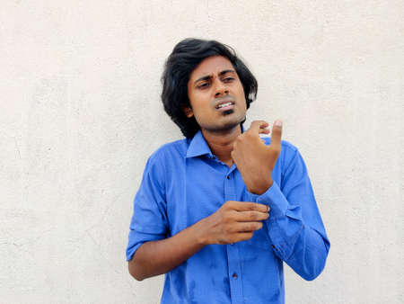 Young south Indian business man buttoning one side sleeve of a blue shirt. Other side folded sleevesの写真素材