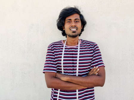 Smiling male tailor with measuring tapes around his neck standing with arms fold. White backgroundの写真素材