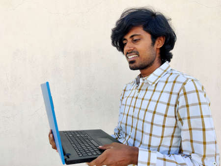 Young south Indian tamil business man wearing white formal shirt is attending video conference in laptop with smile. White backgroundの写真素材