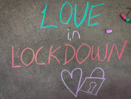 The inscription text on the grey board, Love in lockdown with hand drawn love symbol and lock. Using color chalk pieces.の写真素材