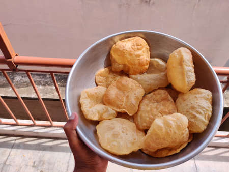 Indian tradtitonal food. Hand holding a bowl full of poori or puri.の写真素材