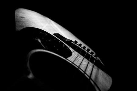 Acoustic guitar on a black background. Black and white photo.