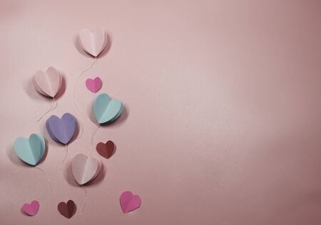 Paper elements in shape of heart flying on pastel pink background, Valentine's Day and lovey concept, copy space for note and textureの写真素材