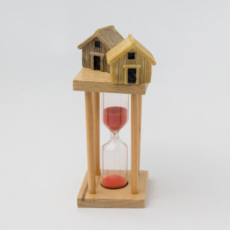 Real estate investment concept. Sand glass and miniature house