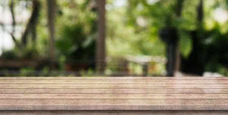 Empty old wood table top with blur nature coffee shop background.