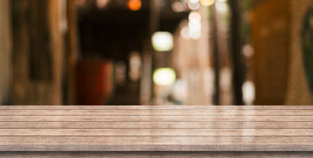 Empty wooden table top with lights bokeh on blur restaurant background.の写真素材