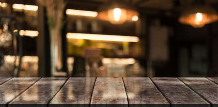 Empty wooden table top with lights bokeh on blur restaurant background.
