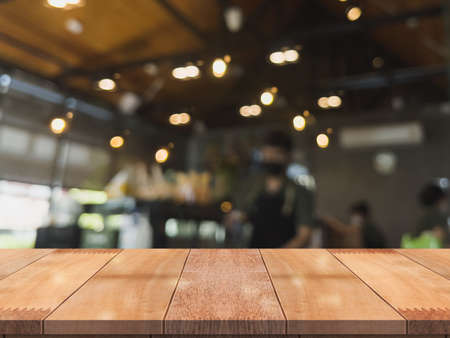 Empty wooden table top with lights bokeh on blur restaurant background.