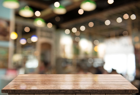 Empty wooden table top with lights bokeh on blur restaurant background.の写真素材