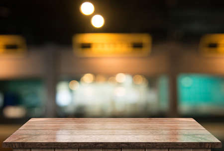 Empty wooden table top with lights bokeh on blur restaurant background.の写真素材