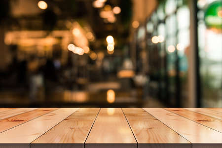 Empty wooden table top with lights bokeh on blur restaurant background.の写真素材