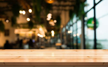 Empty wooden table top with lights bokeh on blur restaurant background.の写真素材
