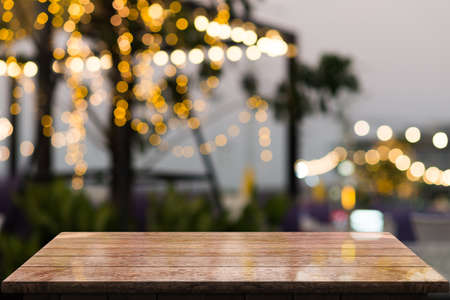 Empty wooden tabletop with lights bokeh on blur restaurant background.の写真素材