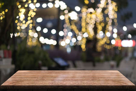 Empty wooden tabletop with lights bokeh on blur restaurant background.の写真素材