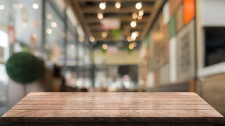 Empty wooden table top with lights bokeh on blur restaurant background.の写真素材