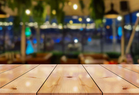 Empty wooden table top with lights bokeh on blur restaurant background.の写真素材