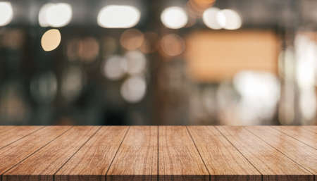 Empty wooden table top with lights bokeh on blur restaurant background.