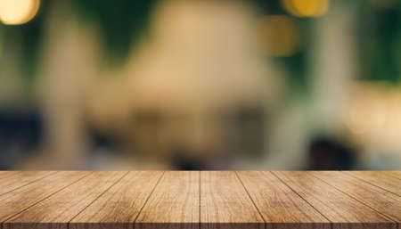Empty wooden table top with lights bokeh on blur restaurant background.