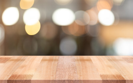 Empty wooden table top with lights bokeh on blur restaurant background.の写真素材