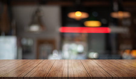 Empty wooden table top with lights bokeh on blur restaurant background.の写真素材