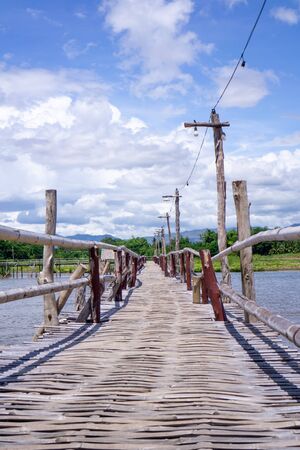 A wooden bridge over the river with a forest background Mountains and blue skiesの写真素材