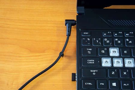 Connecting charger on a black notebook computer.の写真素材
