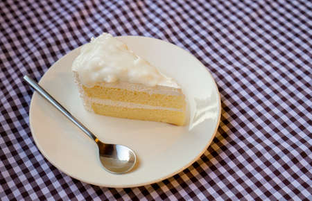 The cakes in white plates were on a table covered with checkered cloth.の写真素材