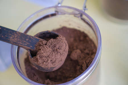 Cocoa powder in a spoon scooped out of a plastic jar.の写真素材