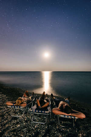 People relax on the beach in the light of moon