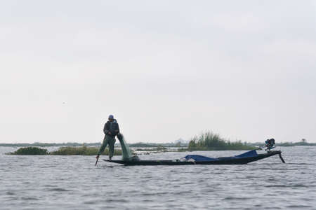 Traditional fisherman on a boat on Inle lake. Leg Rowing Fishermen with net on boat Inle Lake...