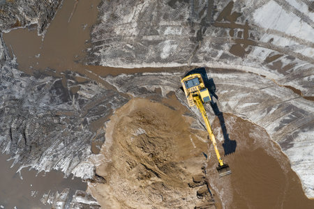 Yellow excavator digger working. Excavator digging sand, ground from water. Industrial aerial drone photo viewの写真素材