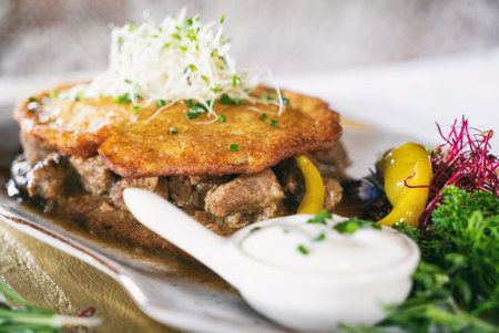 Pried potato pancakes with vegetables on a plate. Dinner main dish on a wooden table. Traditional...