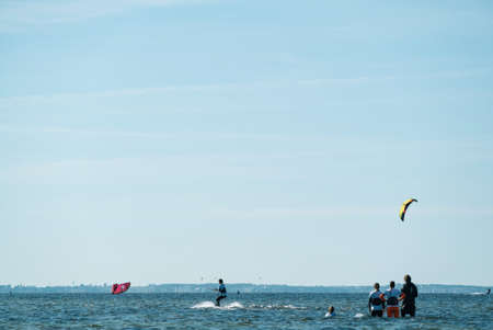 People swim in the sea on a kiteboard or kitesurfing. Summer sport learning how to kitesurf. Kite surfing on Puck bay in Jastarnia, Poland, Europeの写真素材