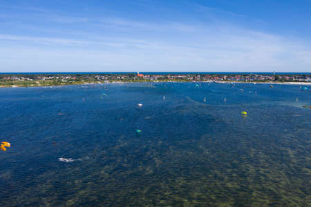 People swim in the sea on a kiteboard or kitesurfing. Summer sport learning how to kitesurf. Kite surfing on Puck bay in Jastarnia, Poland, Europe aerial drone photo viewのeditorial素材