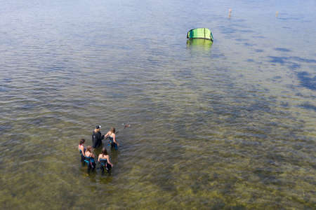 People swim in the sea on a kiteboard or kitesurfing. Summer sport learning how to kitesurf. Kite surfing on Puck bay in Jastarnia, Poland, Europe aerial drone photo viewのeditorial素材