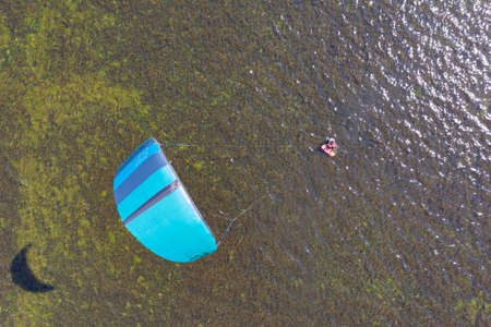 People swim in the sea on a kiteboard or kitesurfing. Summer sport learning how to kitesurf. Kite surfing on Puck bay in Jastarnia, Poland, Europe aerial drone photo viewのeditorial素材