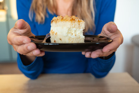 The woman holds food in her hand. The girl holds a cake on a plate. Cake on black plate.の写真素材