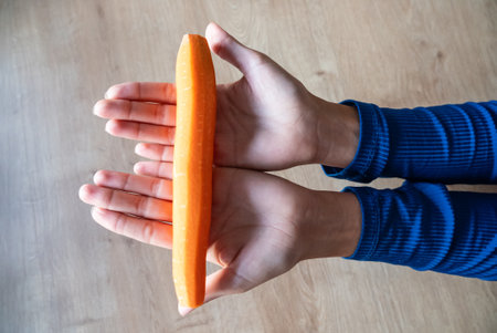 The woman holds food in her hand. the girl holds carrots in her hands. Orange carrots in hand.の写真素材