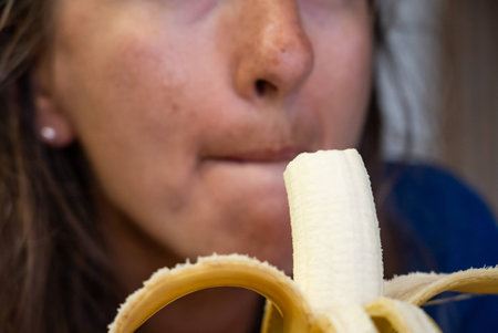 Woman eats food. Woman eats banana. Close shot of girl eating bananas. Face while eating bananaの写真素材