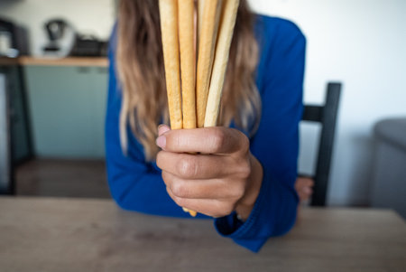 The woman holds food in her hand. Girl holds Grissini in her hands. Italian grissini holding.