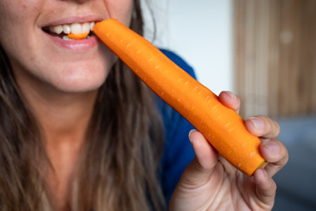 Woman eats food. Woman eats carrot. Close shot of girl eating carrots. Face while eating carrot.の写真素材