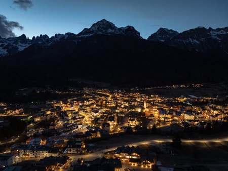 Aerial drone view of Andalo town at night with mountains background in winter. Ski resort Paganella Andalo, Trentino-Alto Adige, Italy., Italian Dolomites,.Pagnella valley. Snow covered Italian Dolomites at winter.の写真素材