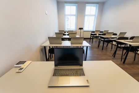 Interior of a modern classroom with desks, chairs and laptops. Empty conference room with laptop on table in office. OfficeBusiness. Conference room with benches, tables and a laptops on the tables.の写真素材