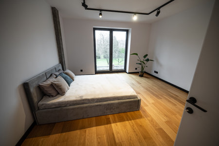 Bedroom with a large comfortable bed. Interior of a newly built house, bedroom with a large, comfortable bed with plush pillows and soft linens, complemented by modern decor and ample natural light.の写真素材